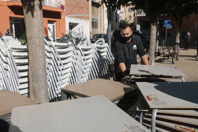 El propietari del bar El Caixer de Vilobí, Jordi López, recollint les cadires i taules aquest 16 d'octubre del 2020. (Horitzontal)