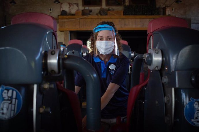 Una trabajadora de PortAventura World protegida con mascarilla y pantalla