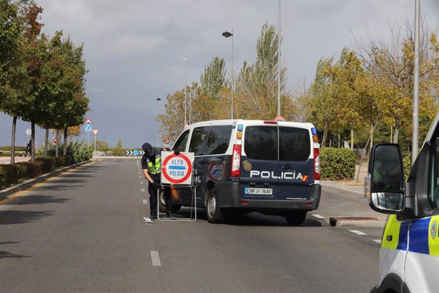 Un agente de la Policía Nacional coloca una señal que indica un control policial en el segundo día de entrada en vigor de las nuevas restricciones de movilidad en el municipio madrileño de Alcorcón.