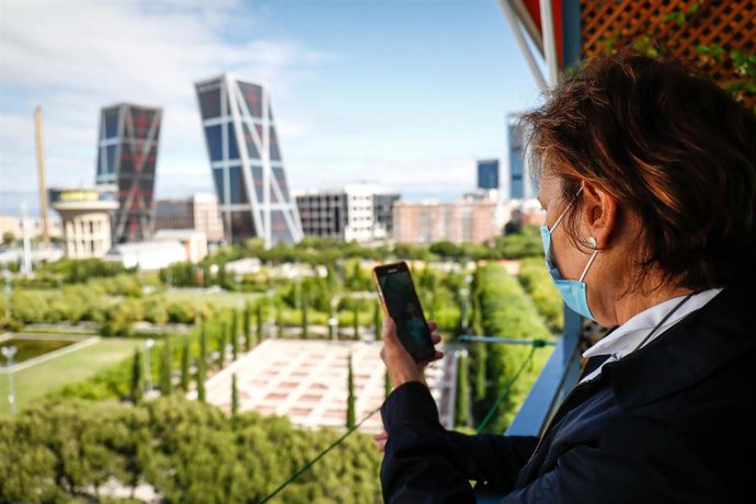 Araceli, usuaria de audífonos intracanales observa su teléfono móvil desde un balcón, durante el confinamiento. En Madrid (España) a 12 de junio de 2020.