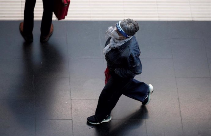 Una mujer protegida con pantalla protectora y mascarilla camina por un andén de la Estación de Tren Príncipe Pío durante el primer día laborable con restricciones de movilidad en toda la capital de Madrid (España), a 5 de octubre de 2020.