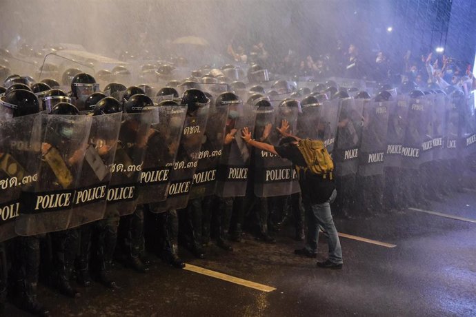 Un manifestante trata de detener una carga policial en Bangkok.
