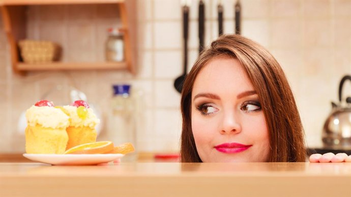 Mujer mirando un pastel con hambre.