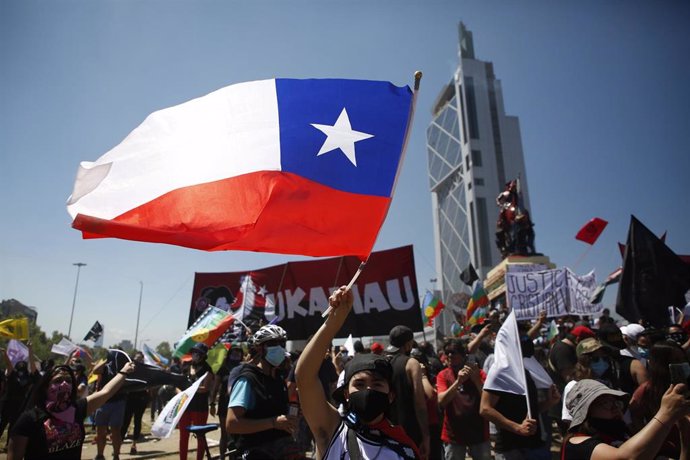 Un manifestante ondea la bandera de Chile durante las protestas por el primer aniversario del estallido social de octubre de 2019.