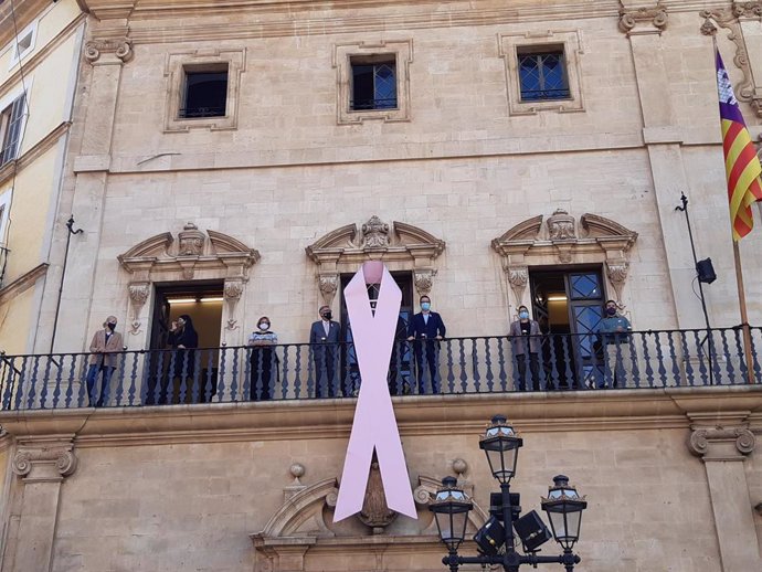 El alcalde de Palma, José Hila, el presidente de la Asociación Española contra el Cáncer de Mama en Baleares, Javier Cortés, y miembros de la corporación municipal han participado en la cuelga del lazo rosa.