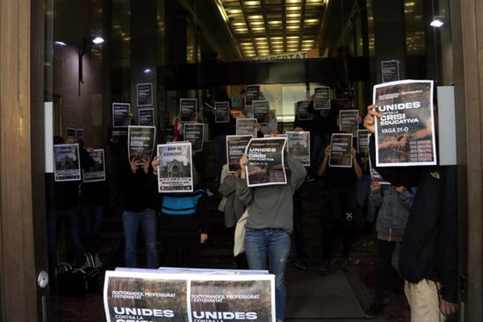 Universitaris del Sindicat d'Estudiants dels Pasos Catalans (SEPC) i de les assemblees de facultat mostren cartells de la vaga del 21 d'octubre a dins de l'entrada del Departament d'Empresa, que han ocupat durant una hora. 19 octubre 2020. (Horitzontal)