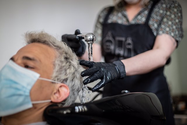 Un hombre se corta el pelo en una peluquería en el día en que estos locales pueden atender con cita previa y con limitación de aforo dentro de la primera fase de desescalada, en Vitoria / Álava / País Vasco (España), a 2 de mayo de 2020.