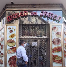 Un hombre mira un cartel situado en el establecimiento del Museo del Jamón en Carrera de San Jerónimo 6.