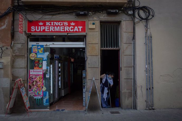 Una mujer friega un portal junto a un supermercado abierto durante el tercer día de la entrada en vigor de las nuevas restricciones en Cataluña, en Barcelona, Cataluña (España) a 19 de octubre de 2020. El pasado viernes 16 de octubre entraron en vigor l