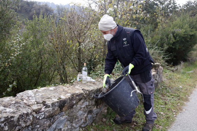 Pla general d'un treballador de la brigada de Les Masies de Roda recollint restes d'un 'botellón' el 20 d'octubre del 2020. (horitzontal)