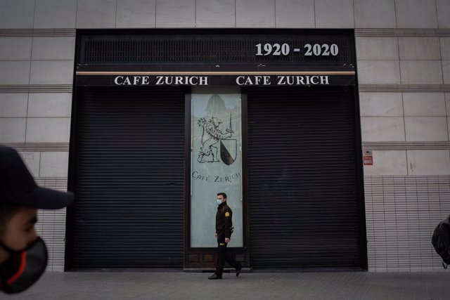 Un guardia de seguridad pasa por delante de una cafetería cerrada durante el tercer día de la entrada en vigor de las nuevas restricciones en Cataluña, en Barcelona, Cataluña (España) a 19 de octubre de 2020. El pasado viernes 16 de octubre entraron en vi