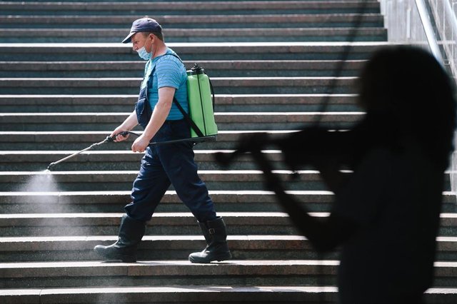 Un trabajador desinfecta una escalera en un edificio público en Moscú