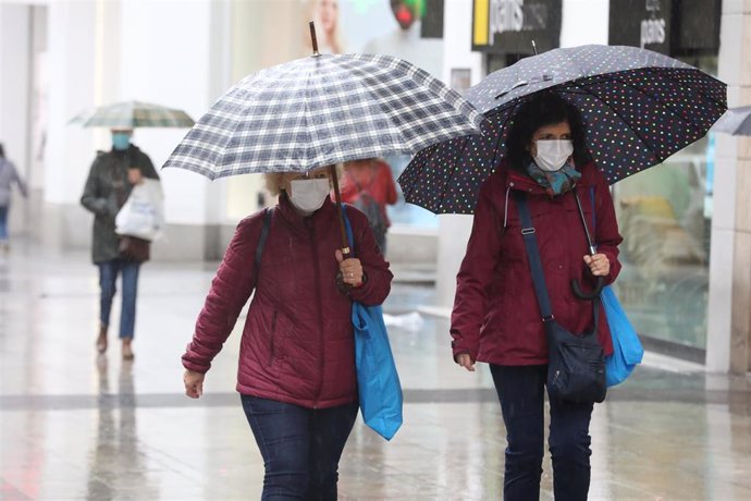 Dos mujeres protegidas con un paraguas caminan por el centro de la capital, en Madrid (España), a 20 de octubre de 2020.  Una treintena de provincias estarán este martes 20 de octubre en riesgo naranja (importante) y riesgo amarillo (bajo) por precipita