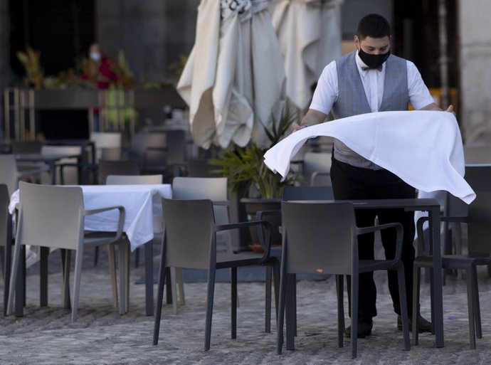 Un cambrer prepara la taula d'una terrassa d'un establiment