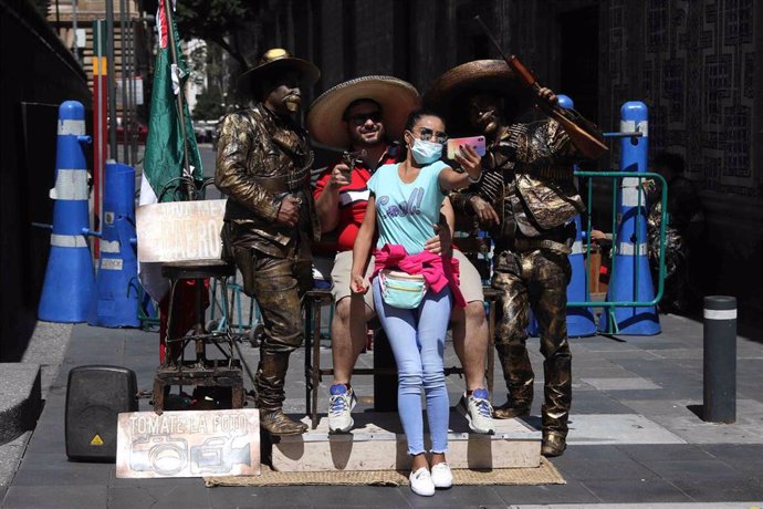 Un grupo de turistas se fotografían junto a unas estatuas situadas en el centro histórico de Ciudad de México.