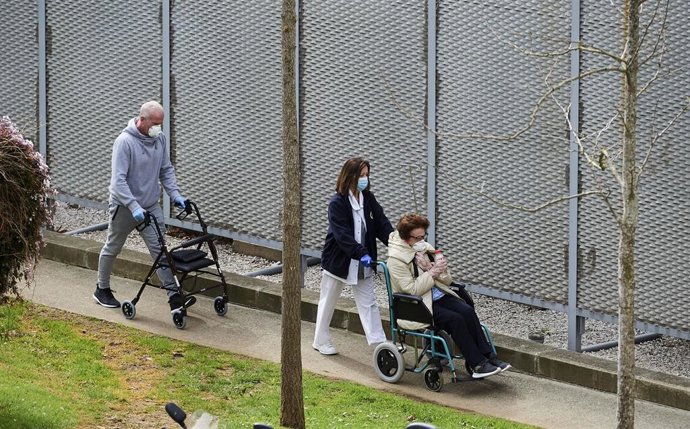 Una profesional sanitaria pasea con pacientes del Hospital Valdecilla. Archivo