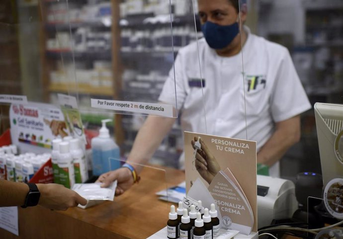 Un farmacéutico entrega a un cliente una de las mascarillas KN95 que ha recibido en su farmacia, en Madrid (España), a 30 de septiembre.