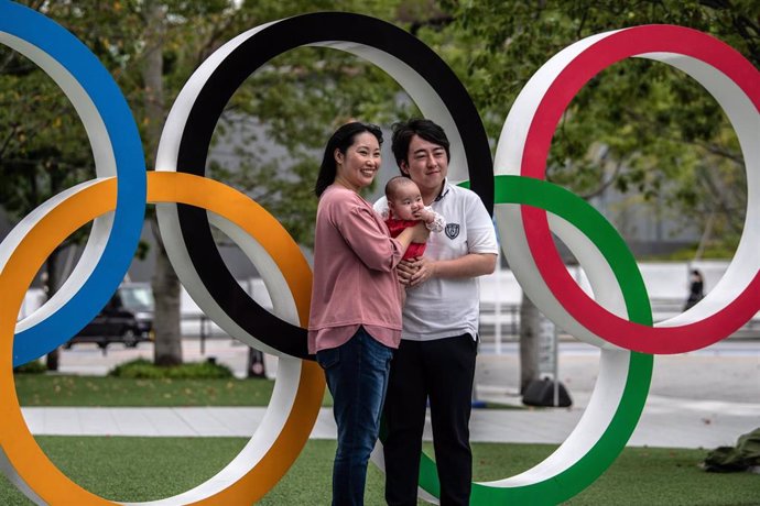Una pareja posa con su hijo junto a los anillos olímpicos en Tokio