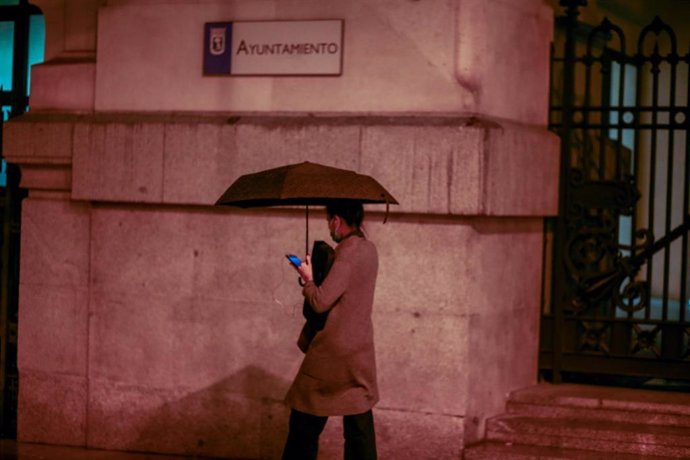 Una persona camina bajo un paraguas junto al Ayuntamiento de Madrid un día marcado por una bajada de temperaturas y lluvias, en Madrid (España), a 20 de octubre de 2020. Una treintena de provincias estarán este martes 20 de octubre en riesgo naranja (im