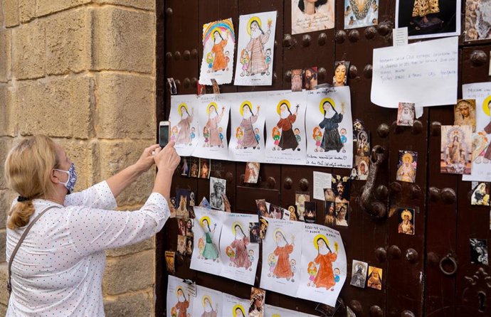 Ciudadanos observan y fotografía los dibujos que los niños del barrio han colocado  en la puerta del convento de Sor Ángela de la Cruz por las monjas contagiadas 
