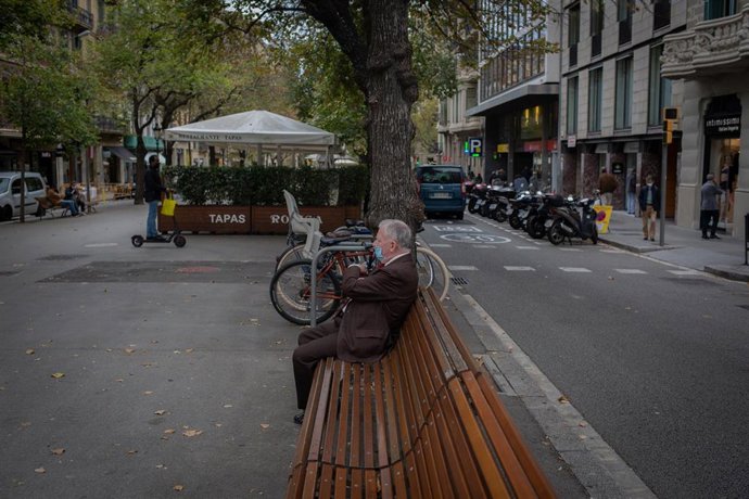Un hombre descansa en un banco durante el cuarto día de la entrada en vigor de las nuevas restricciones en Cataluña, en Barcelona, Cataluña (España) a 20 de octubre de 2020.