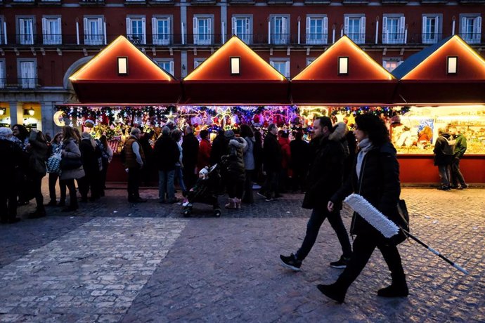 Turistas y vecinos de Madrid visitan los puestos del mercadillo navideño de la Plaza Mayor de Madrid.