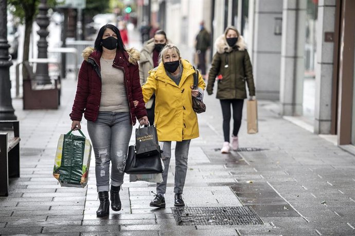 Dos personas usando mascarilla pasean por una ciudad española.