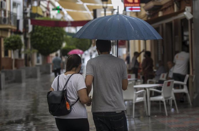 Una pareja se protege de la lluvia bajo su paraguas en Tomares (Sevilla, Andalucía, España), a 18 de septiembre de 2020.