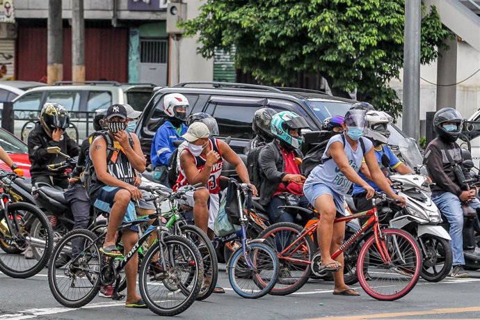 Un grupo de motoristas y ciclistas esperan para poder cruzar en una de las vías de Manila, Filipinas.