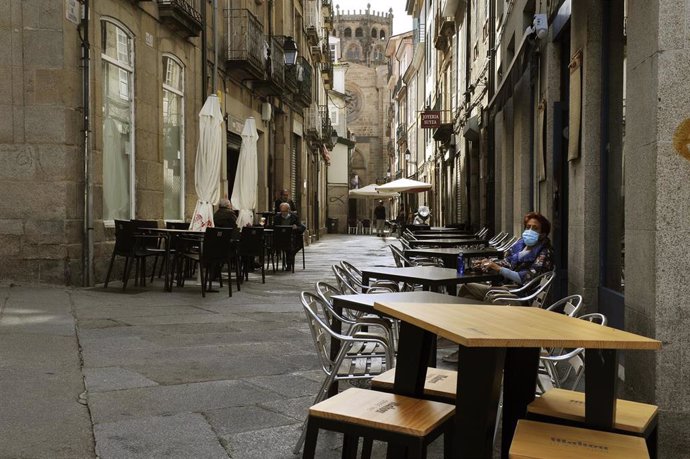 Una mujer permanece sentada en una terraza del barrio de O Couto en Ourense.