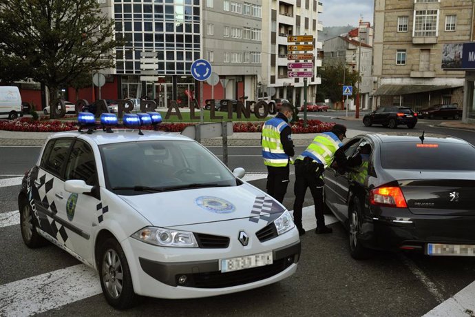 Dos agentes paran a un vehículo en un control realizado en O Carballiño, Ourense, Galicia (España), a 15 de octubre de 2020. Desde hoy, la Xunta limita las entradas y salidas de las localidades orensanas de Carballiño, O Irixo y Boborás, que quedan deli