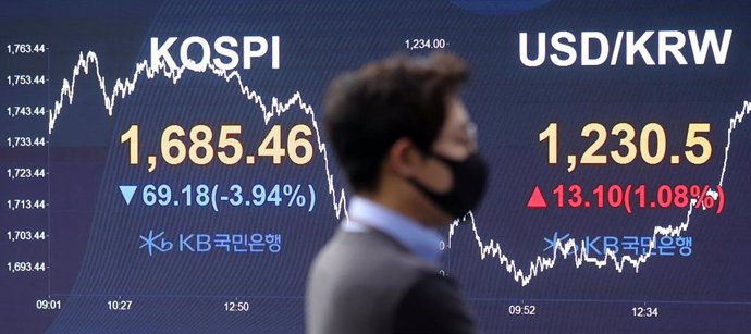 01 April 2020, South Korea, Seoul: A stock exchange trader wearing a face mask looks at a financial data monitor in the Hana Bank room. 