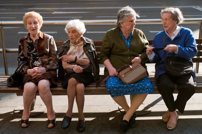 Cuatro mujeres mayores sentadas en un banco. 