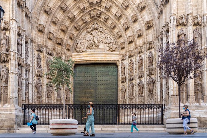 Paseantes por la puerta de la Anunciación de la Catedral de Sevilla en el primer día  de uso obligatorio de mascarillas en Sevilla a 15 de julio del 2020