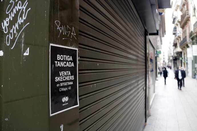 El cartell d'un comer tancat a l'Eix Comercial de Lleida en primer pla i el carrer amb gent de fons. Imatge del 20 d'octubre de 2020. (Horitzontal)