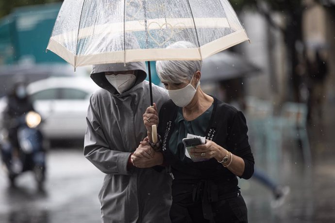 Dos personas se protegen de la lluvia bajo un paraguas en Sevilla.