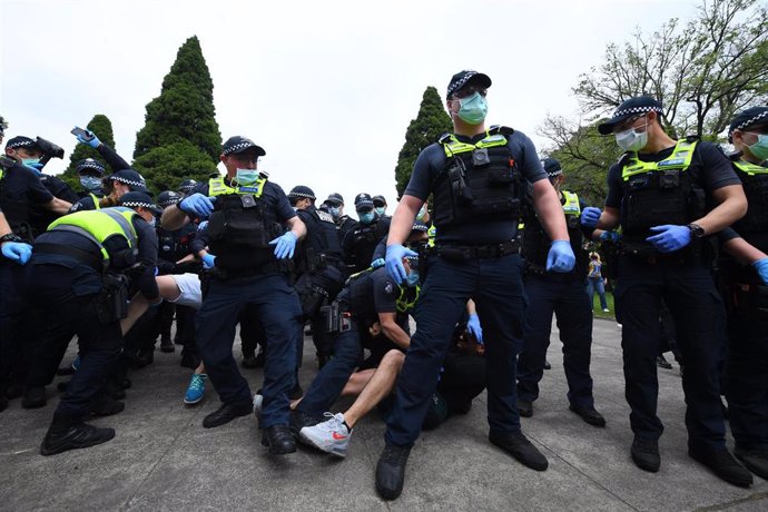Policías con mascarilla y guantes actuando contra manifestantes en una protesta contra el confinamiento en Melbourne, en Australia