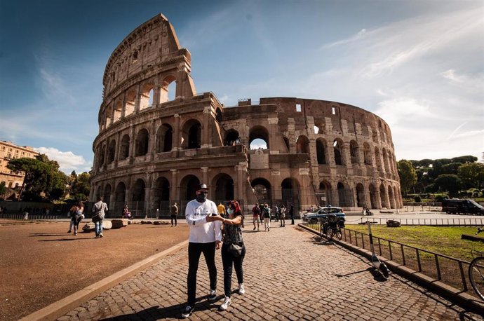 Dos personas con mascarilla junto al Coliseo en Roma