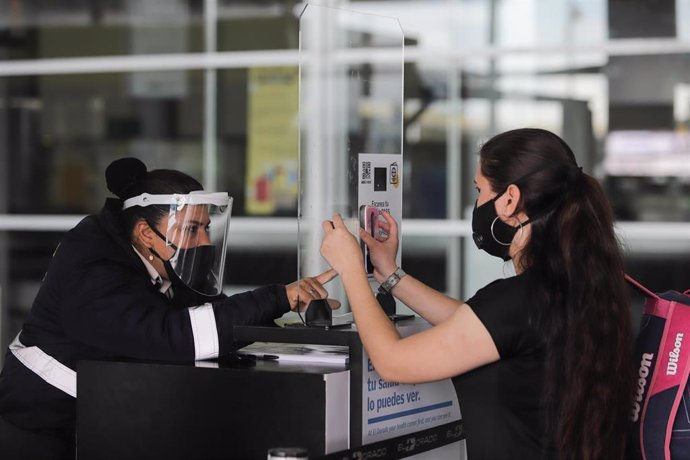 Una mujer es atendida por otra en un mostrador en el aeropuerto de Bogotá