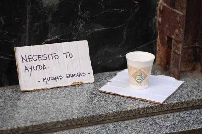 Un cartel de un mendigo pidiendo limosna en un vaso de café para llevar.