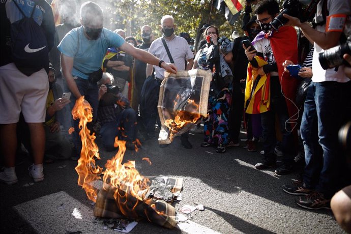 Manifestantes independentistas queman fotografías de Felipe VI y el presidente del Gobierno, Pedro Sánchez, durante una concentración de protesta por su presencia en Barcelona.