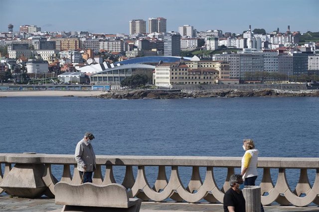 Dos personas pasean por el paseo marítimo de A Coruña, con el estadio de Riazor de fondo, en el segundo día en que el Gobierno permite salir a hacer deporte de forma individual y pasear con otra persona con la que se conviva, a 3 de mayo de 2020.