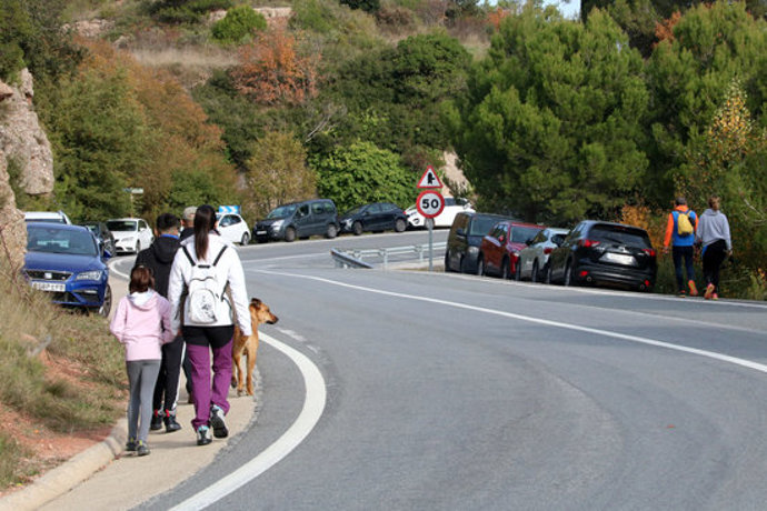 Gran pla general de la carretera d'accés a Montserrat des del Bruc, amb el voral ple de cotxes i excursionistes caminant. Imatge del 25 d'octubre del 2020 (horitzontal)