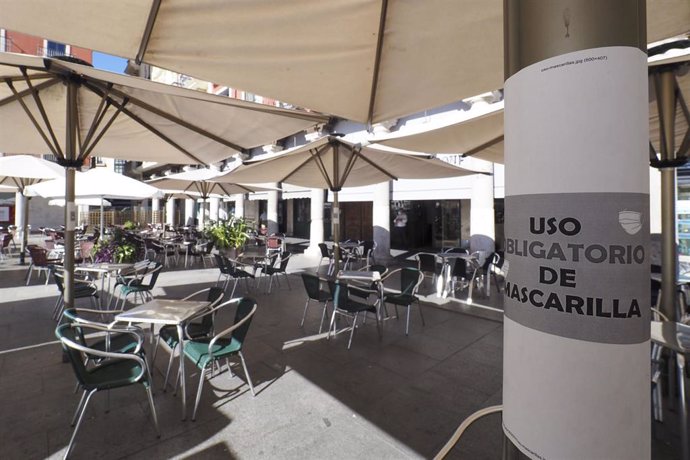 Cartel en el que se lee 'Uso obligatorio de mascarilla' junto a una terraza de un bar en la Plaza Mayor de Valladolid.  .