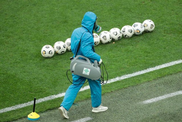 Un trabajador con traje protector y con mascara antigás en un estadio de fútbol de Rusia