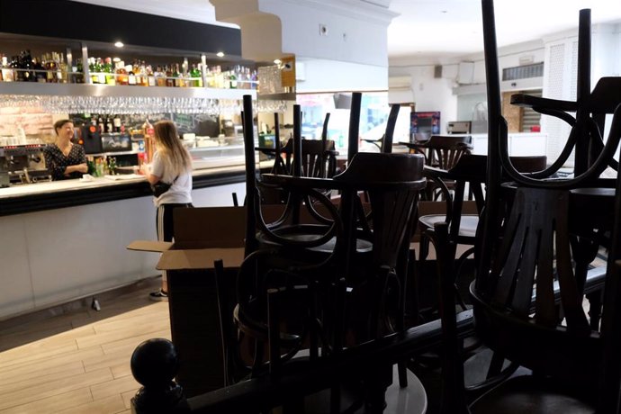 Un local de hostelería con las sillas y mesas apiladas en el interior.