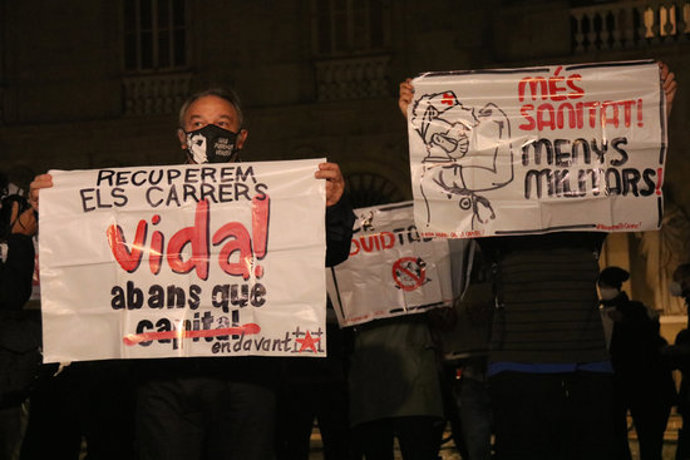 Dos manfiestants de l'esquerra independentista amb cartells contra el toc de queda i a favor de la sanitat pública. 26 d'octubre del 2020. (Horitzontal)