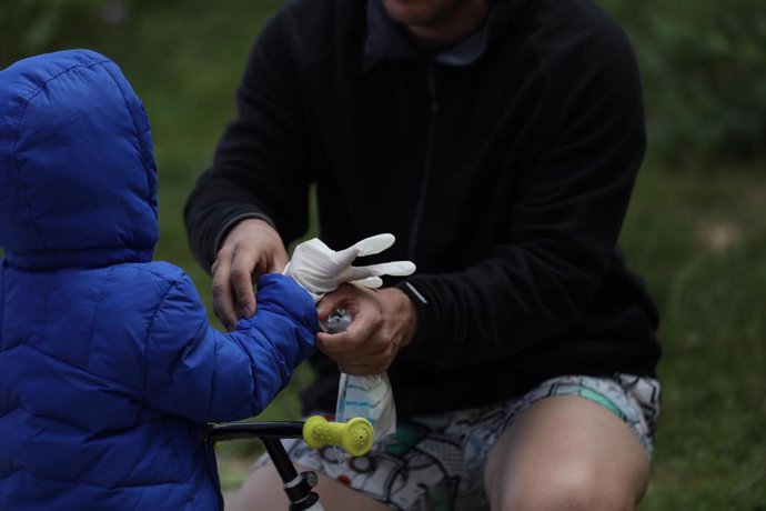 Un padre le pone a su hijo unos guantes.