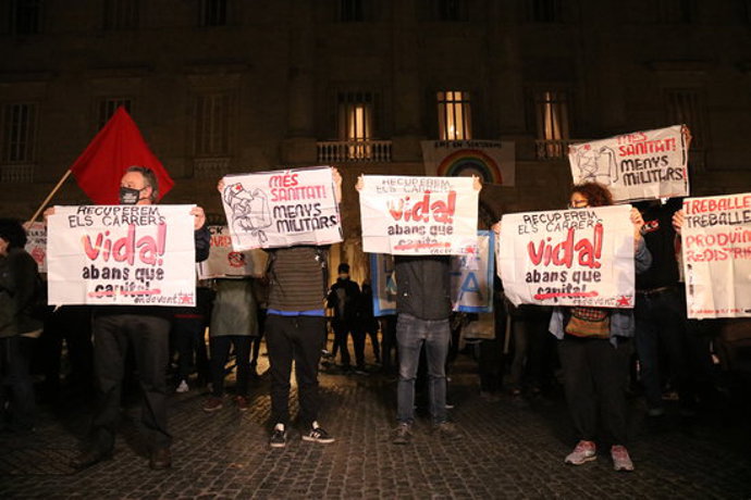 Diverses persones mostren cartells contra les restriccions administratives per intentar frenar la covid-19 en una concentració a Barcelona el 26 d'octubre del 2020. Pla general. (Horitzontal)