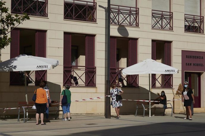 Varias vecinas de la localidad de Peralta visitan a sus familiares desde el exterior de una residencia de mayores, en Peralta